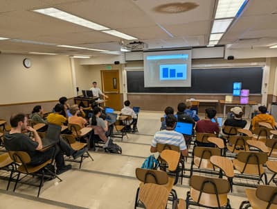 classroom with people facing projector and presenter on lectern