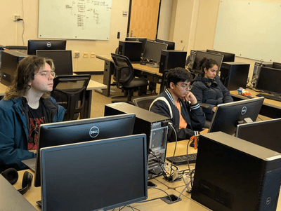 three people in a computer lab, distracted